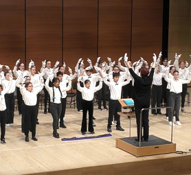 foto del coro sspg aldeno che canta "Blu" con le braccia alzate sul palco del concorso