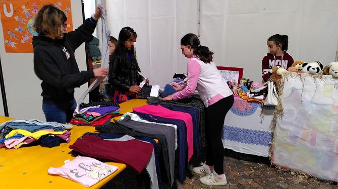 Foto del mercatino del riuso con studenti che allestiscono il reparto dei vestiti