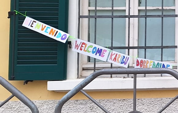 Particolare di una foto degli striscioni con le scritte "benvenuto" in diverse lingue