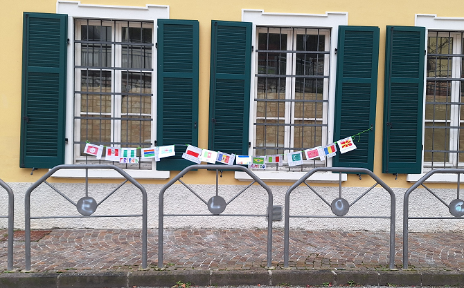 Foto delle finestre della Scuola con lo striscione fatto di bandiere